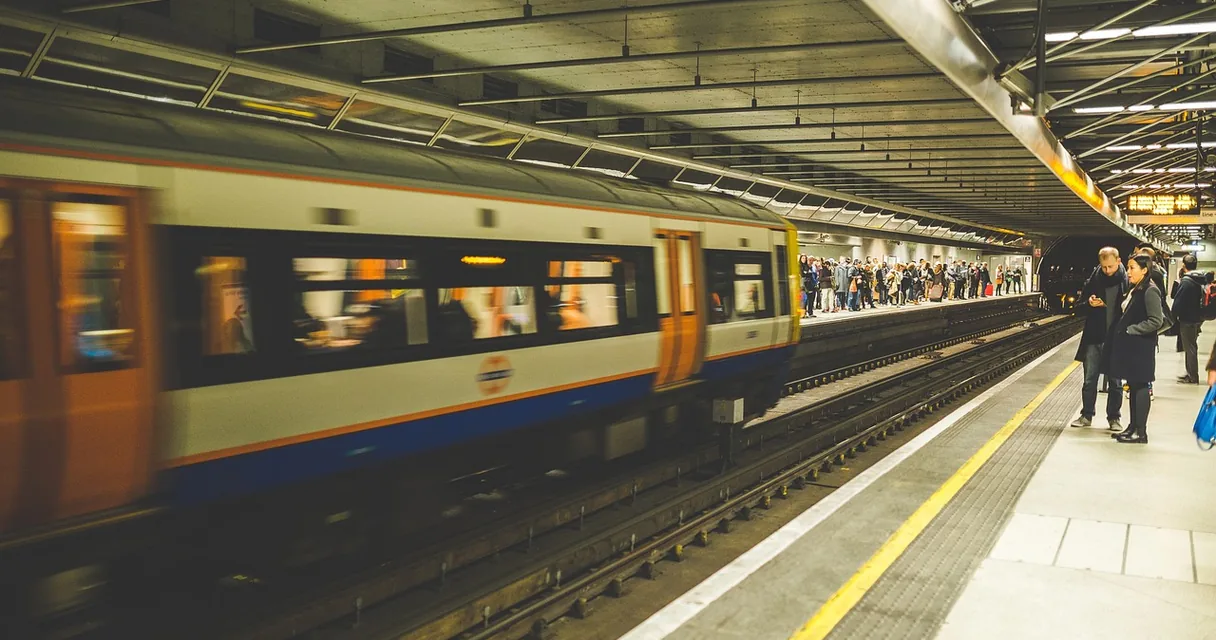 Trem passando em uma plataforma de metrô com passageiros esperando, ilustrando o horário de pico no IPTV